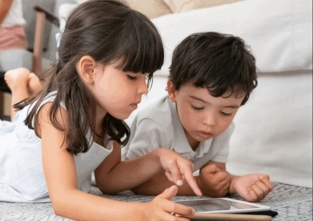 ילדה וילדה שוכבים על שטיח ומסתכלים במסך